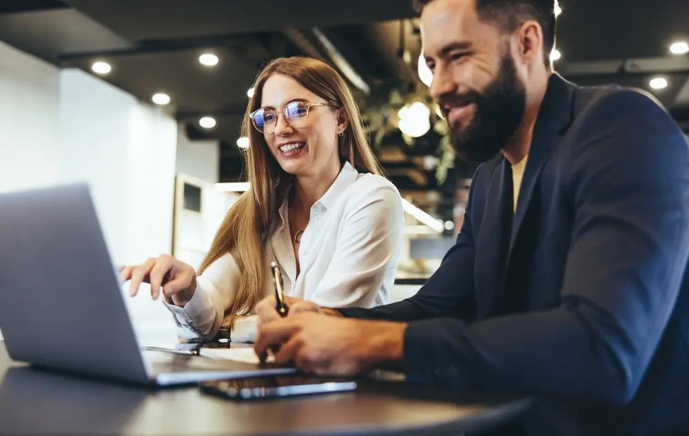Zwei Personen arbeiten gemeinsam am Laptop in einem Coworking Space